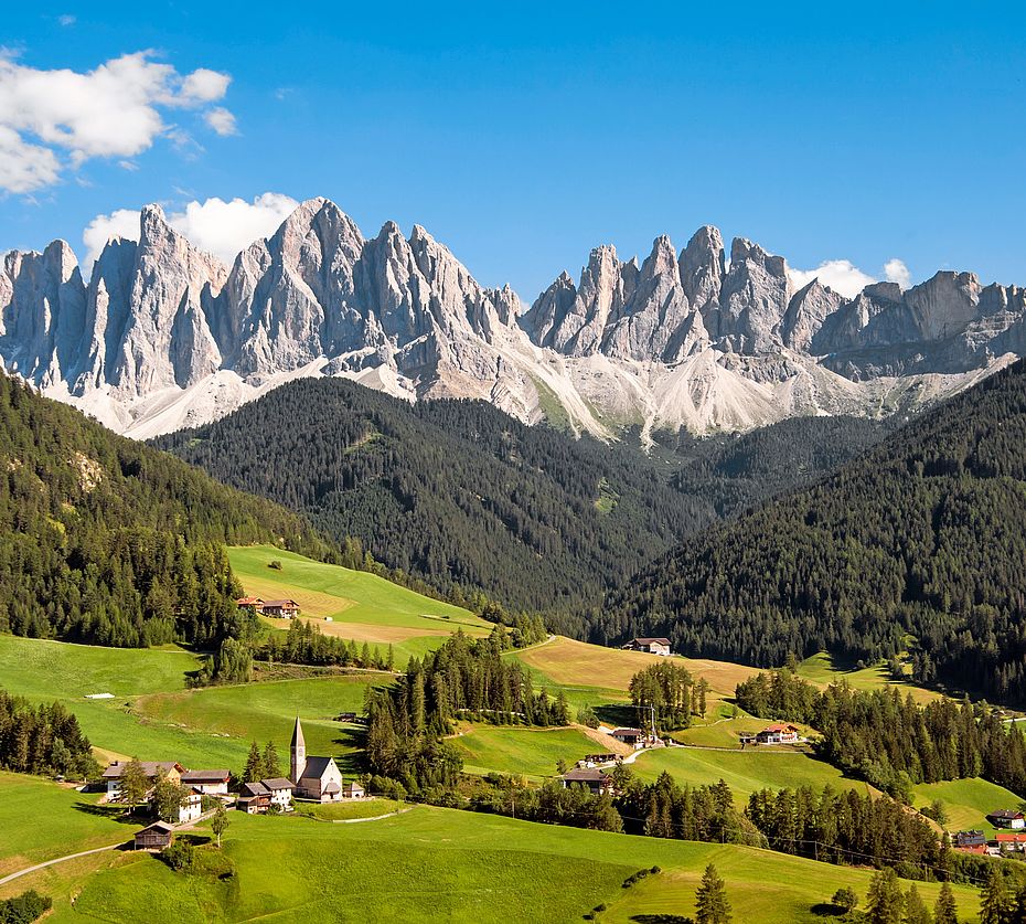 Panoramablick auf die Geislerspitzen in den Dolomiten mit dem Dorf St. Magdalena in Villnöss und grünen Almwiesen